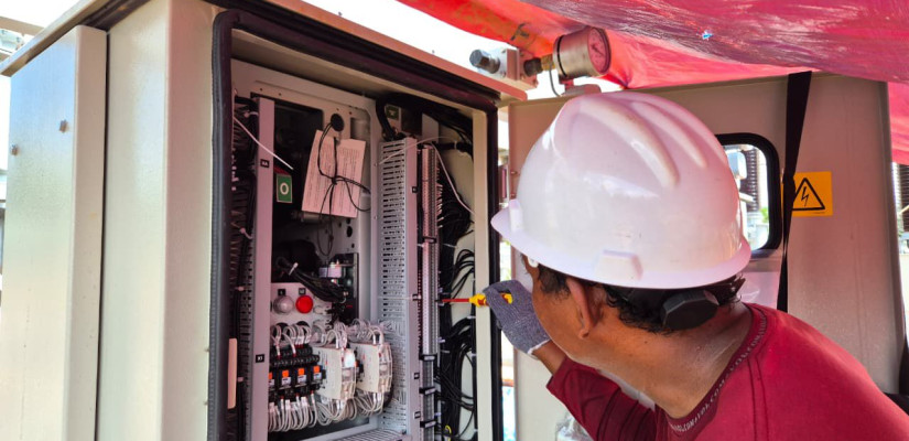 Pekerja sedang melakukan pekerjaan wiring cable pada panel kontrol listrik. Ist